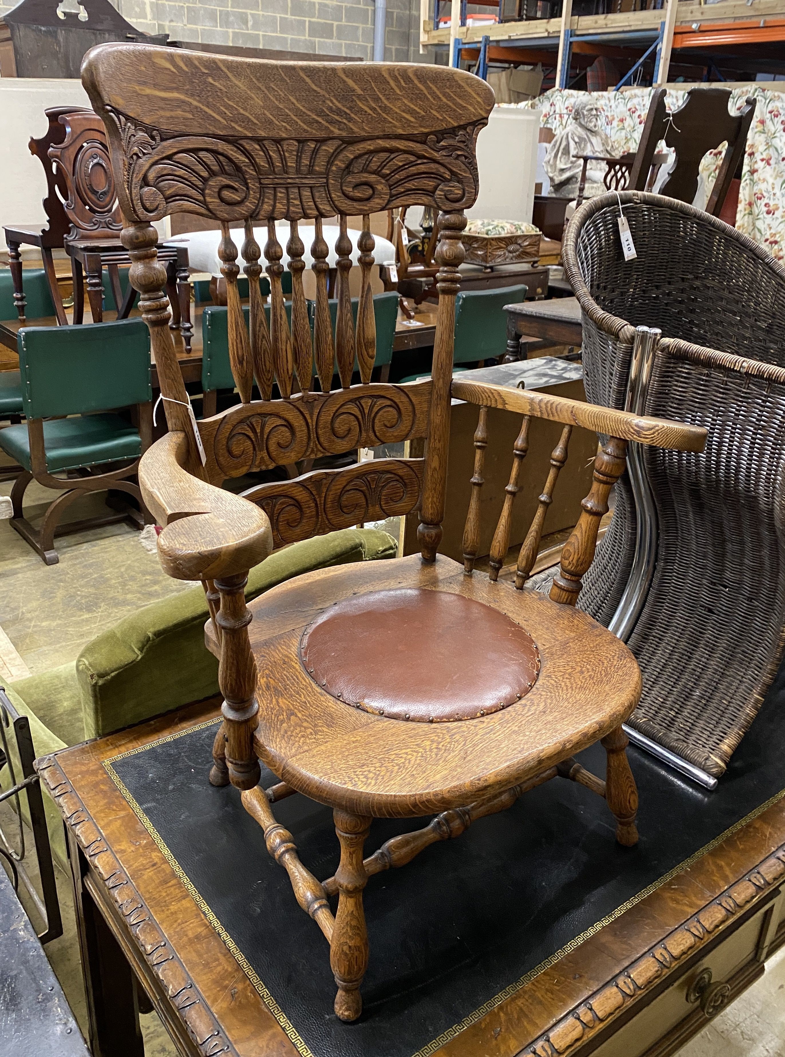 An early 20th century oak low seat elbow chair, width 75cm, depth 48cm, height 97cm